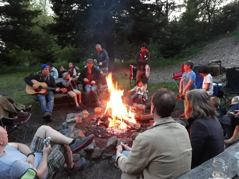 people sitting around a lit campfire